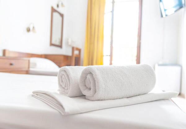 Two white towels are on the bed in hotel room. Close-up horizontal background. Space for text.